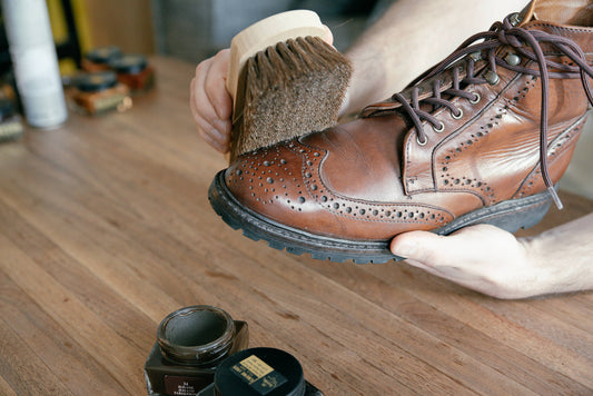 Allen Edmonds Long Branch CXL boot getting brushed with horse hair brush for cover photo. Saphir polish in the background