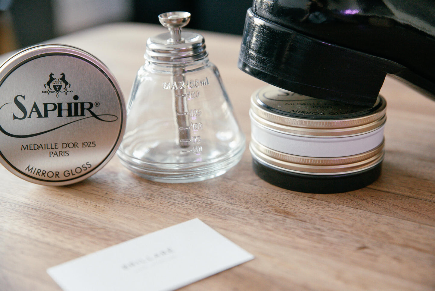 Brillaré water drop glass dispenser for polishing shoes and boots displayed with a tom ford oxford shoe and saphir medaille d'or mirror gloss paste wax polish